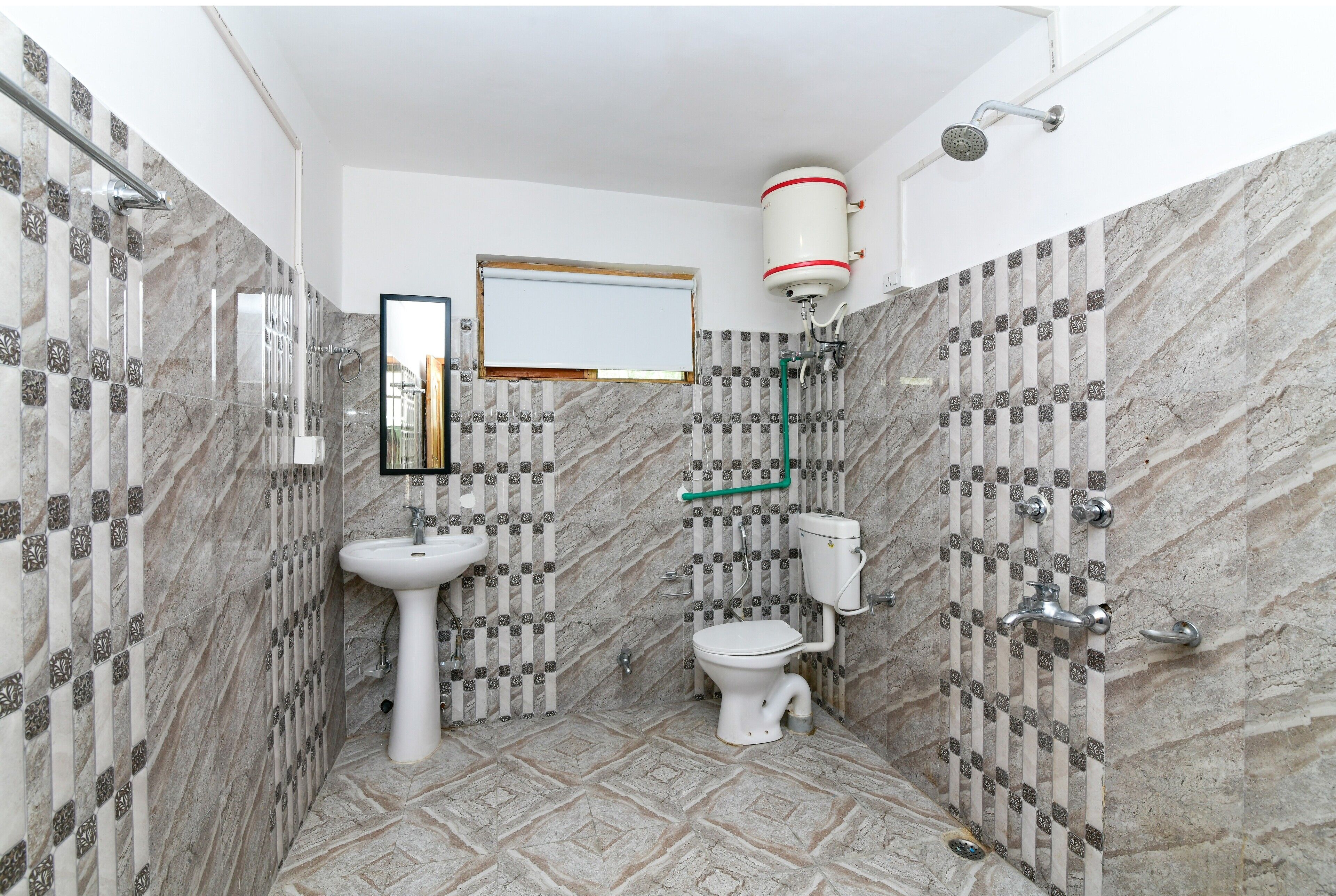 Un baño con suelo de mármol, un lavabo blanco, un inodoro y una ducha.
