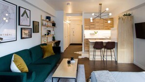 A modern apartment with a green sofa, a small dining area, and a kitchen.
