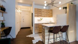 A modern kitchen with wooden cabinets, a central island with bar stools, a hanging light fixture, and a cowhide rug.