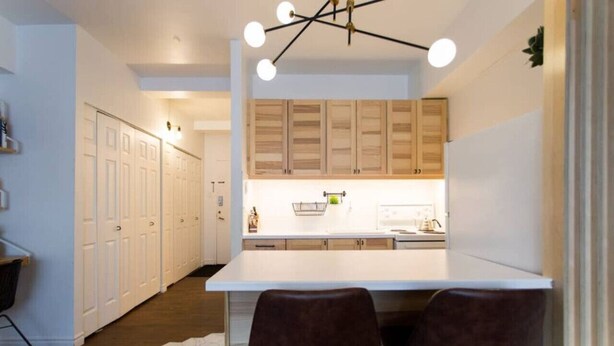 A modern kitchen with white cabinets, a central island, and two brown chairs.