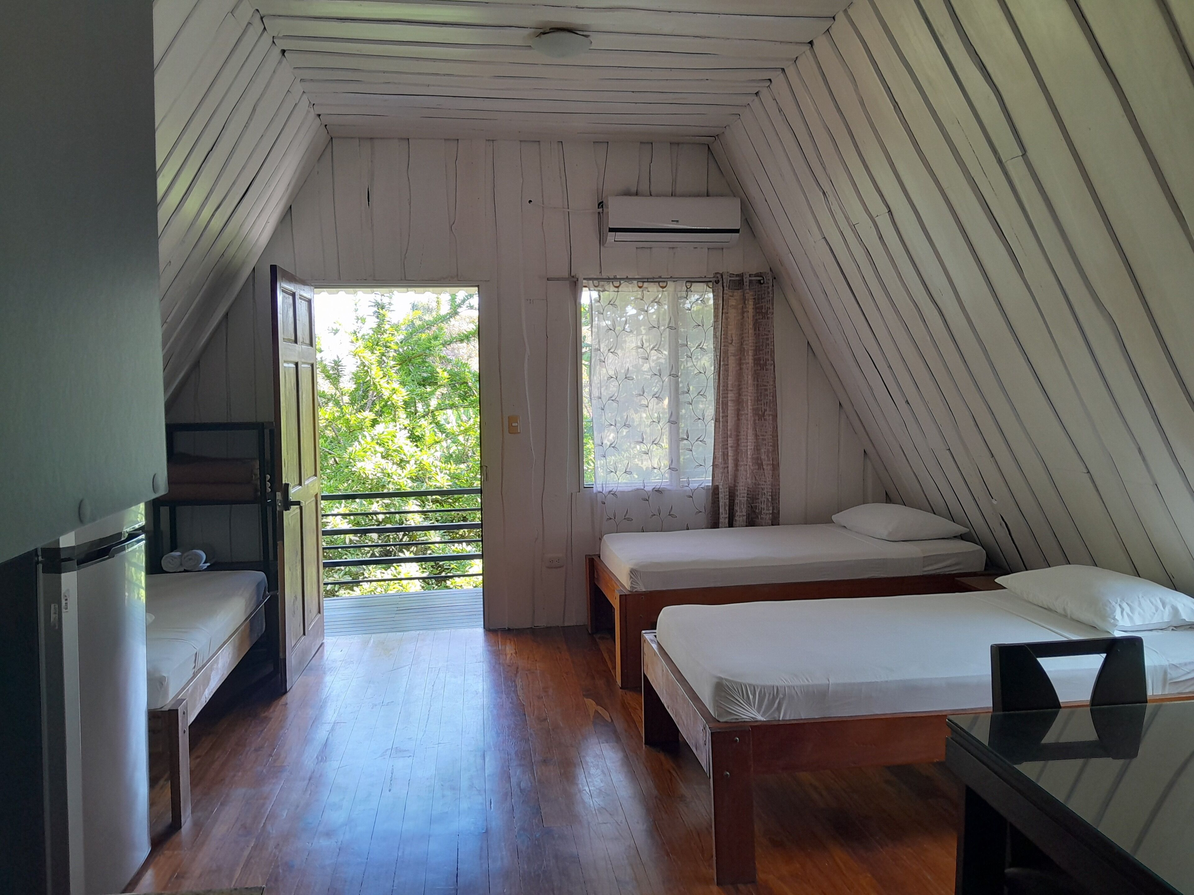 A room with two beds, a small table, and a window with curtains.