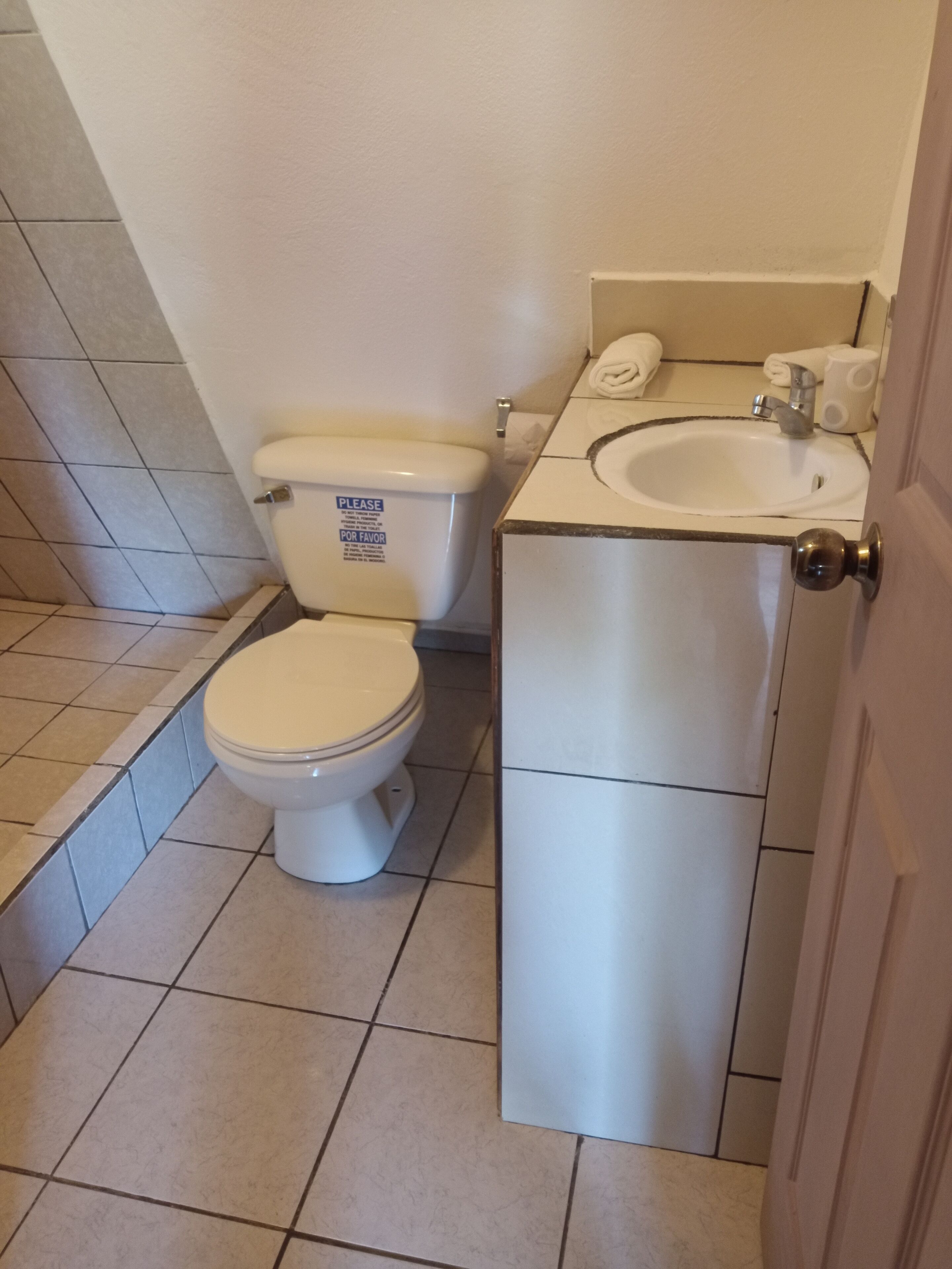 Un baño con inodoro, lavamanos y piso de baldosas.