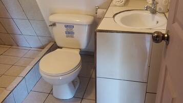 Un baño con inodoro, lavamanos y piso de baldosas.