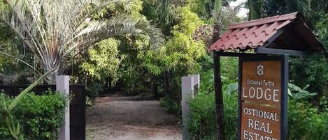 A pathway leading to a lodge with a sign indicating it is an Ostional Turtle Lodge.
