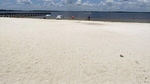 A beach with a clear sky and a wooden pier extending into the water.