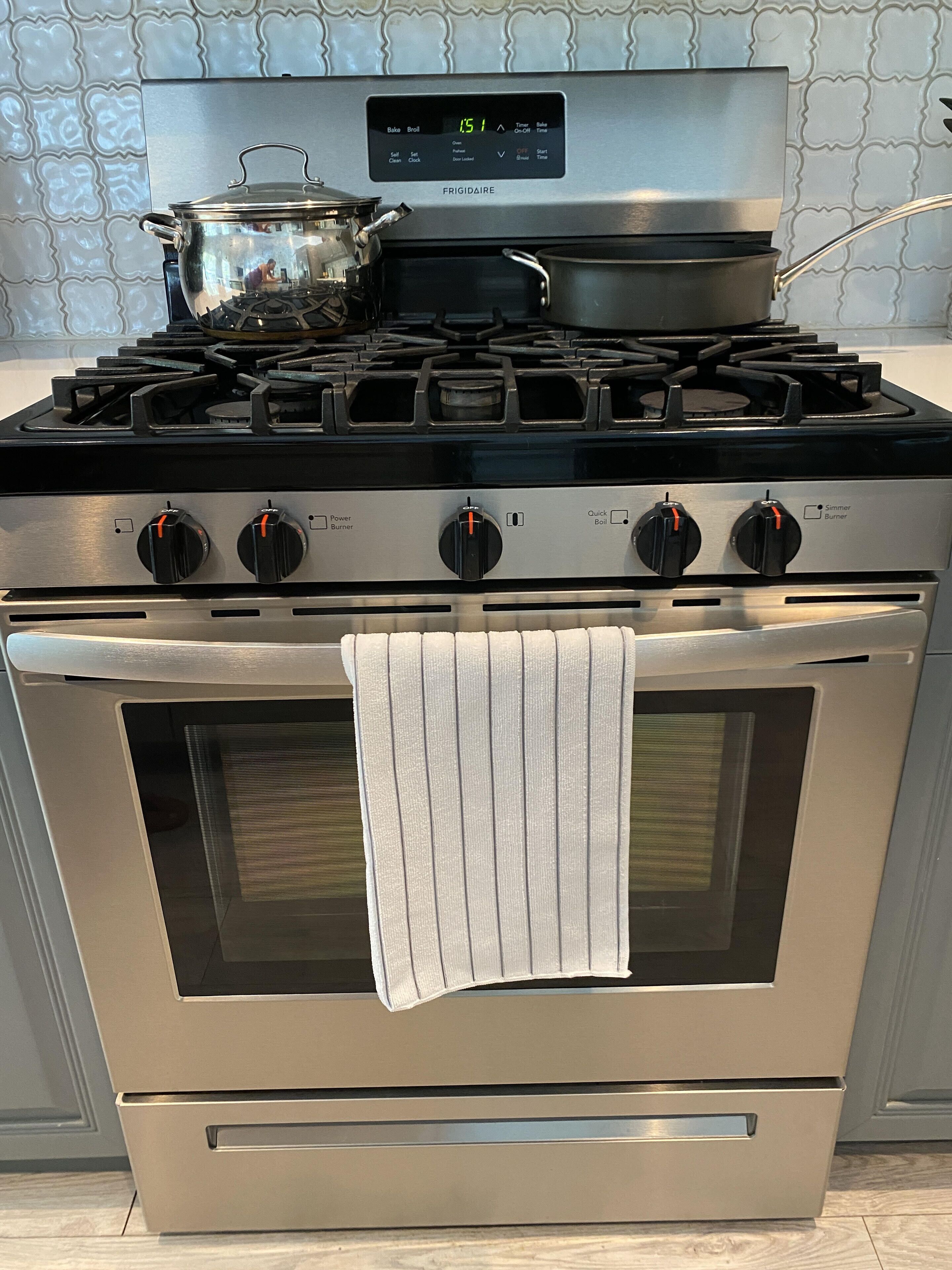 Uma cozinha com fogão de aço inoxidável, forno e uma panela no fogão.