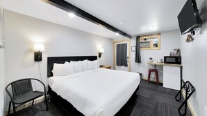 Una habitación de hotel con una cama grande, un escritorio con computadora, una silla y un televisor montado en la pared.