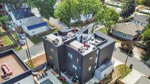 A modern multi-story building with a rooftop pool, outdoor seating, and a small garden area. - Stunning Home with Pool/Outdoor Kitchen, Game Room, BBQ (charlotte)