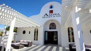 Amira Resort & Spa har en vit fasad, välvda dörröppningar och ett utomhusområde med sittplatser.