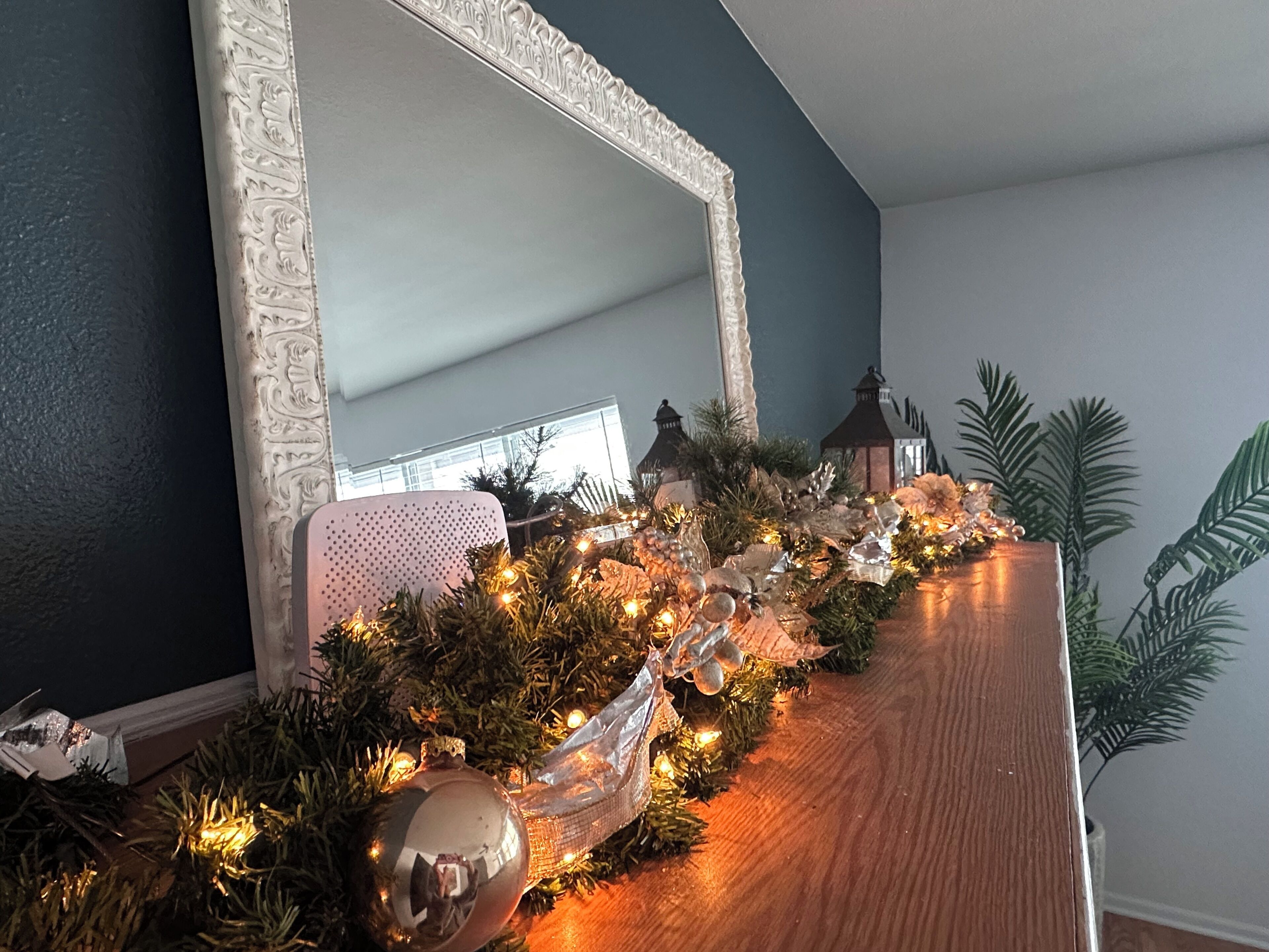 Una habitació amb un armari de fusta, un mirall amb una estructura ornamentada i una decoració festiva amb llums i ornaments.