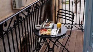 Un balcón con una mesa lista para el desayuno, que incluye un vaso de jugo de naranja, un tazón de cereal y un plato de comida.