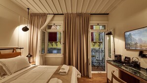 Una habitación de hotel con cama, escritorio, silla, un cuadro y un balcón con vistas.