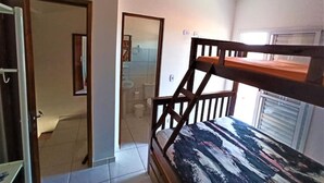 A room with a bunk bed, a door leading to a bathroom, and a window.