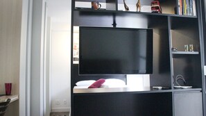 Moderni olohuone, jossa on seinälle asennettu taulutelevisio ja musta viihdekeskus.