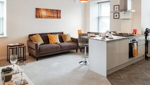 A modern kitchen with a central island, a sofa with cushions, and a dining area with a table and chairs. - 2 bedroom accommodation in Falkland (Falkland)