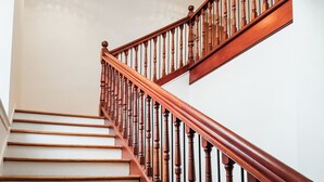 A wooden staircase with a handrail and a light fixture above. - 2 bedroom accommodation in Falkland (Falkland)