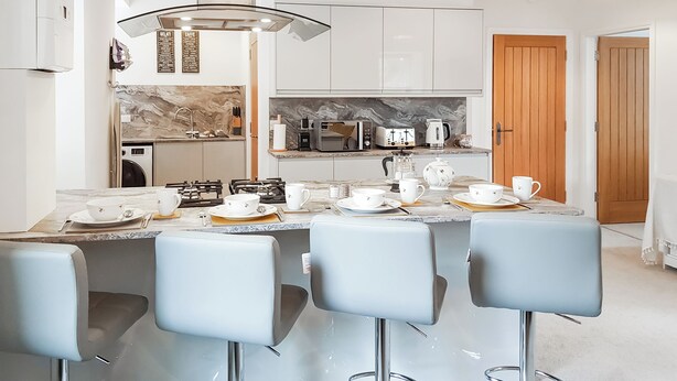 A modern kitchen with a central island, white cabinets, and a marble backsplash. - 2 bedroom accommodation in Falkland (Falkland)