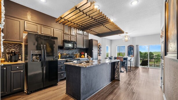 A modern kitchen with a central island, stainless steel appliances, and a view to the outside. - Newly Redesigned Lakefront Condo with Dock near Downtown Fun! (Hot Springs)