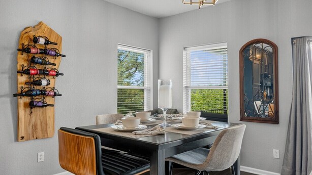 A dining area with a wooden wine rack, a table set with white plates and glasses, and two chairs.