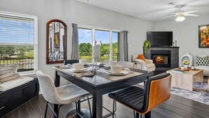 A modern living room with a fireplace, dining area, and a balcony with a view. - Newly Redesigned Lakefront Condo with Dock near Downtown Fun! (Hot Springs)