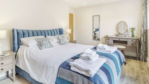 Ein Hotelzimmer mit einem Bett, Nachttischen, einem Schminktisch, einem Spiegel und einer Deckenleuchte.