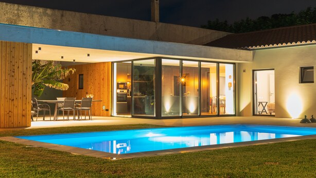 A modern house with a swimming pool, large glass doors, and a patio area. - Casa Familiar com Piscina (Ponta Delgada)