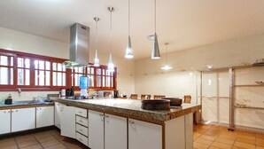 A kitchen with a central island, white cabinets, a stainless steel range hood, and pendant lighting. - Sítio King - Bragança Paulista (Piracaia)