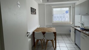 A compact kitchen with a wooden table and chairs, a window with a view, and a sink. - Erft Apartment (Kerpen)