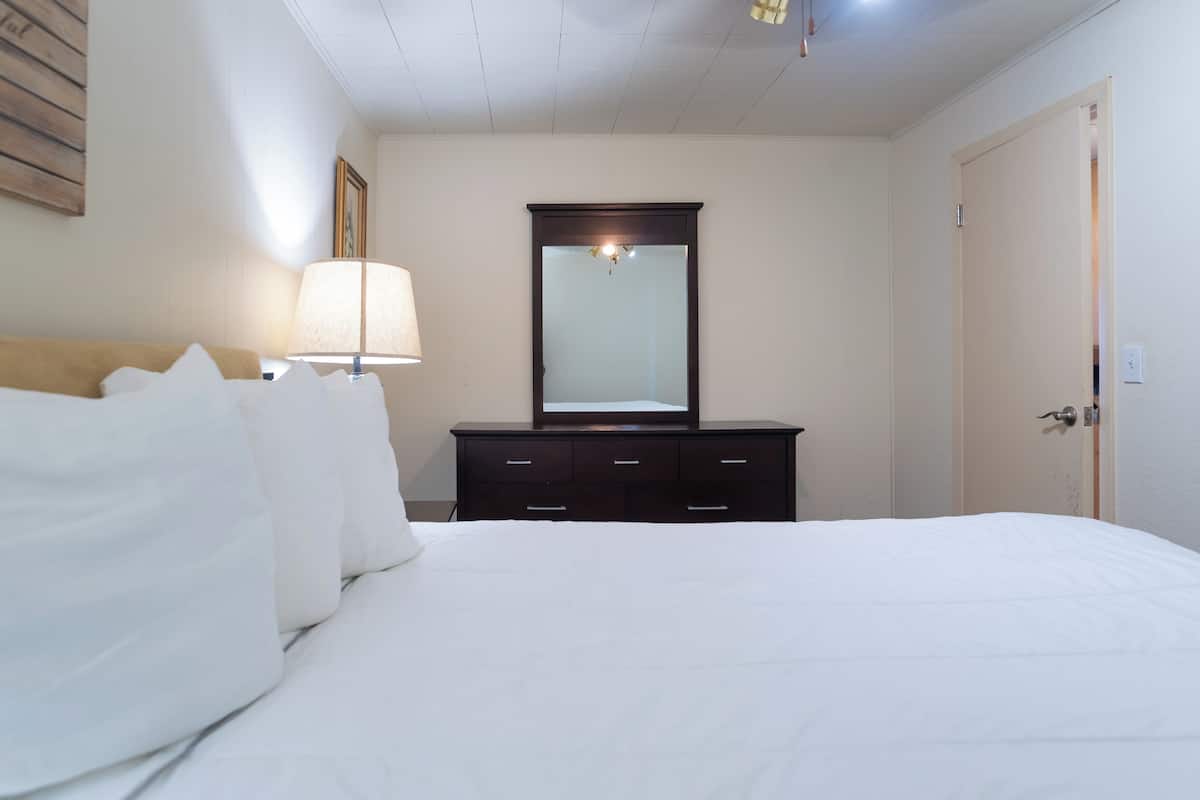 Ein Hotelzimmer mit einem großen Bett, einem Schminktisch, einem Spiegel und einer Lampe.