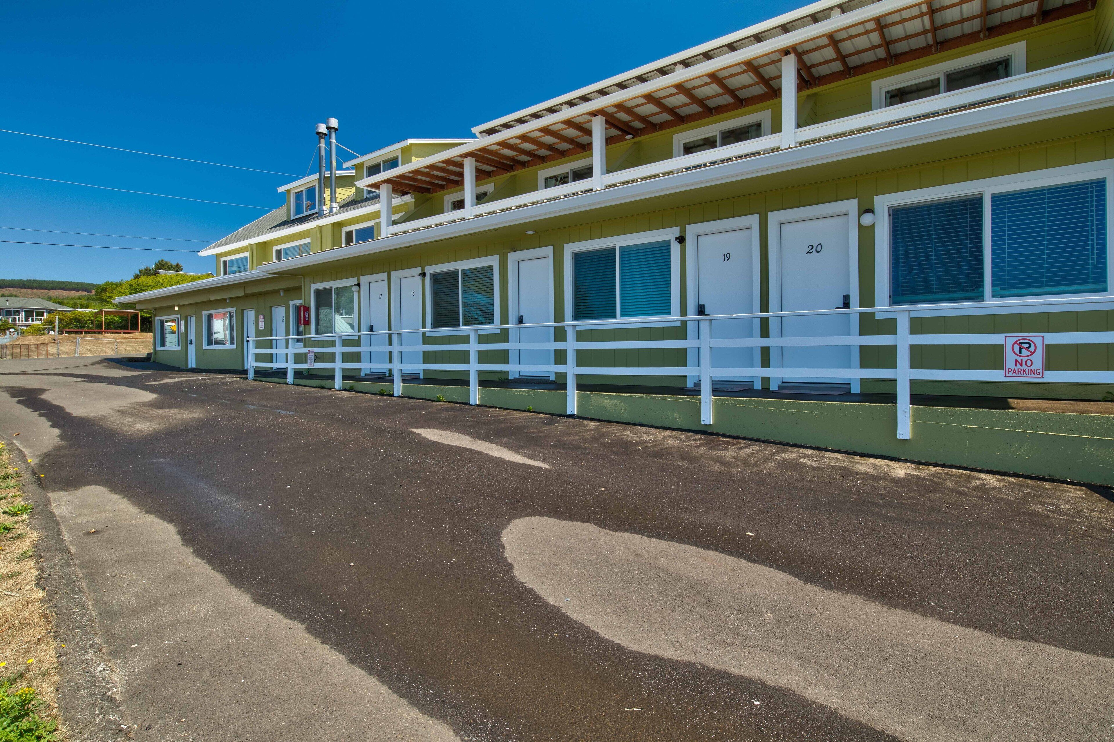 A row of motel rooms with white railings and a 'No Parking' sign.