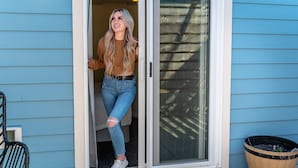 A person stepping out of a blue house with a sliding glass door. - Terimore Bayfront Inn (Tillamook)