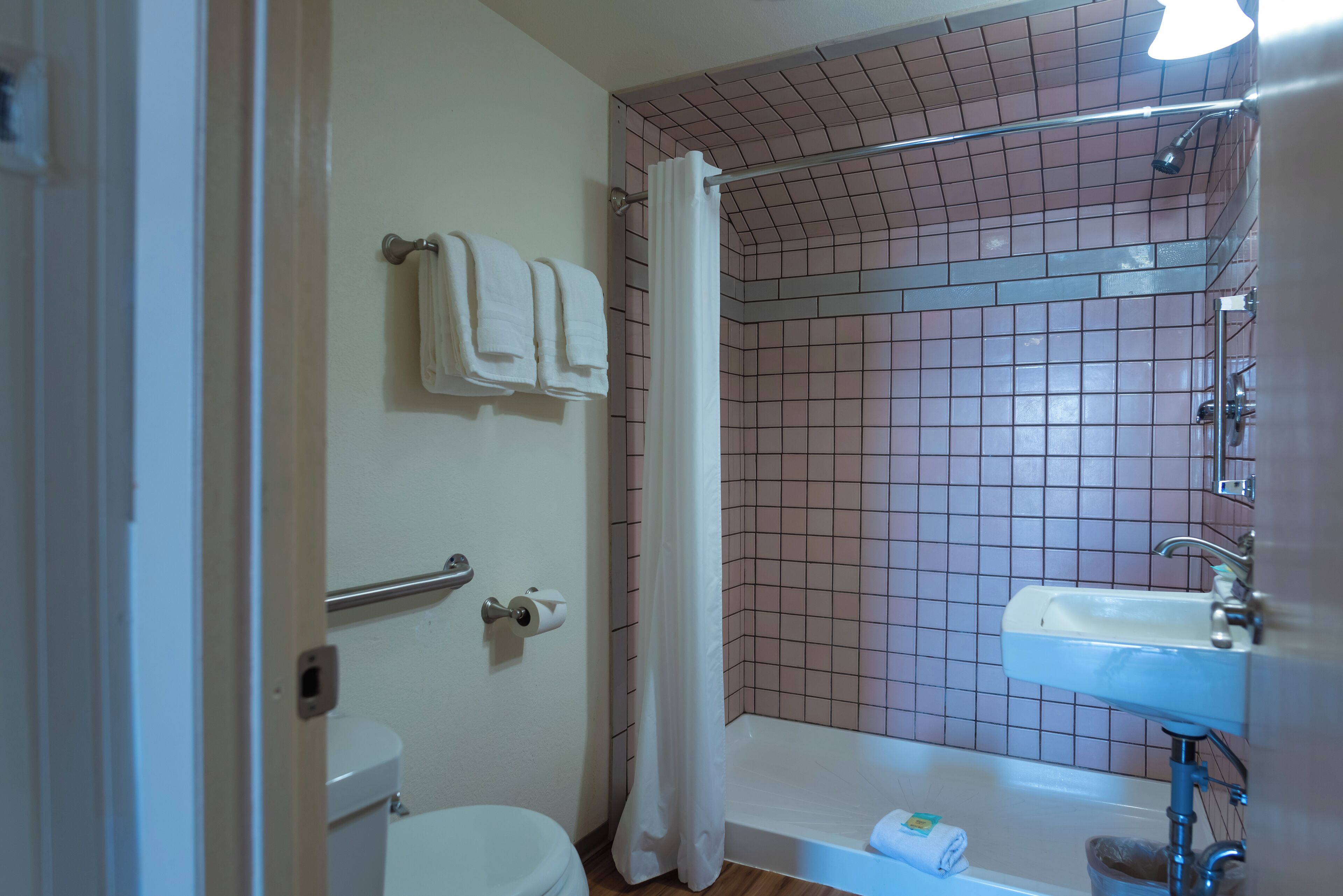 Un baño con inodoro, lavamanos y zona de ducha con pared de azulejos y cortina.