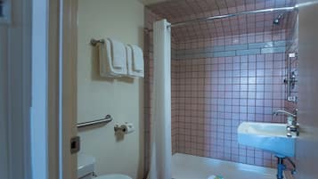 A bathroom with a toilet, a sink, and a shower area with a tiled wall and a curtain.