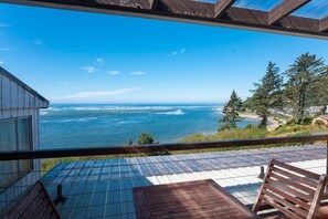 A wooden deck with a view of the ocean and a forested hillside.