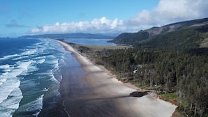 A coastal landscape with a beach, forested hills, and a clear sky. - Terimore Bayfront Inn (Tillamook)