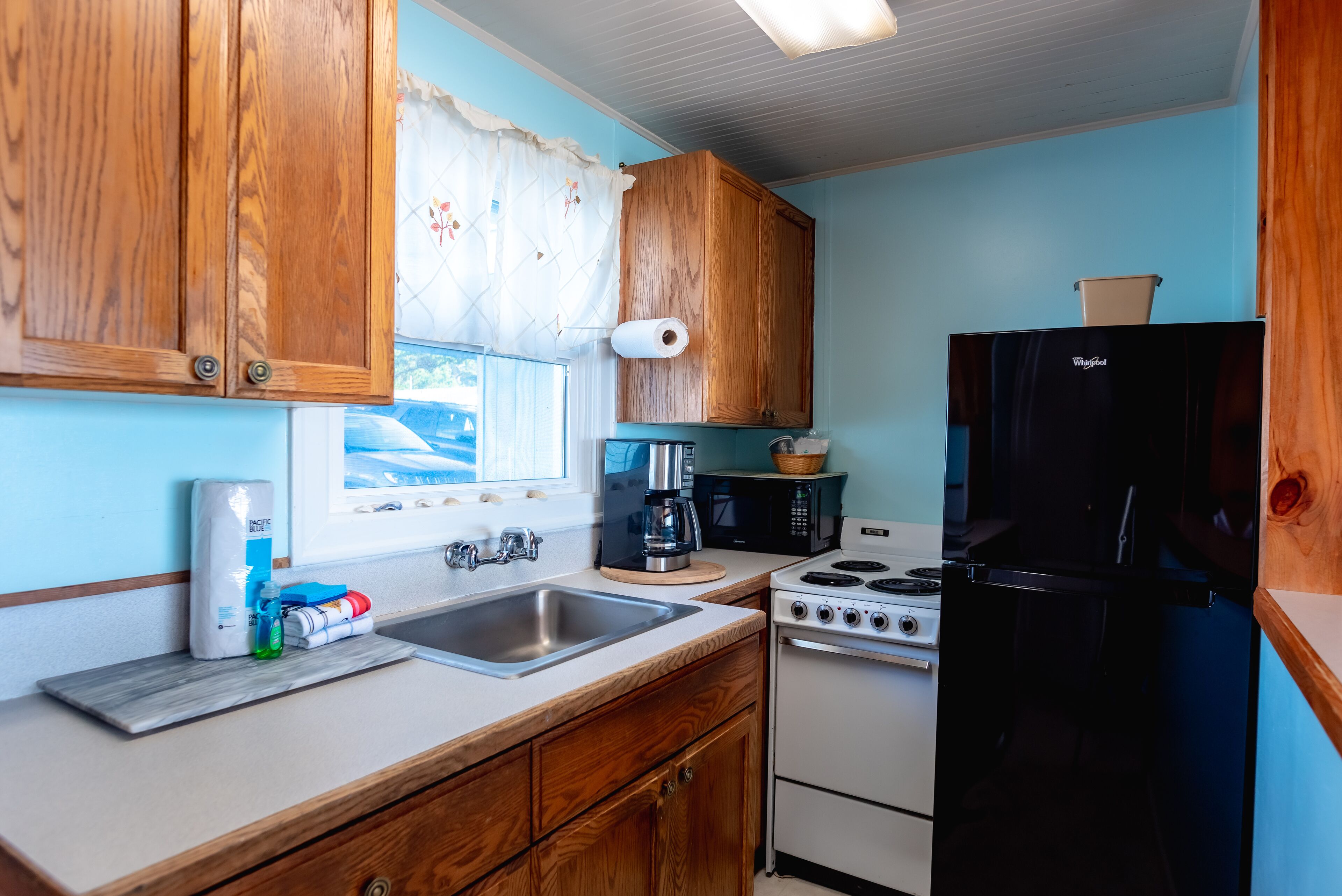 Una cocina compacta con armarios de madera, un lavamanos, una estufa y un refrigerador.