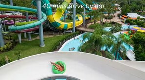 Parque acuático con múltiples toboganes y piscinas, rodeado de vegetación.
