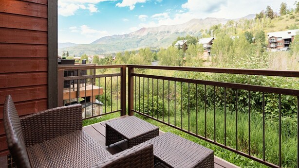A wooden deck with wicker furniture overlooking a mountainous landscape. - Mountain Vista: Beautiful Basecamp @ Meadows Lift (Mountain Village)