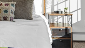 A bedroom with a bed, pillows, a nightstand, a lamp, and a window with blinds. - Mountain Vista: Beautiful Basecamp @ Meadows Lift (Mountain Village)