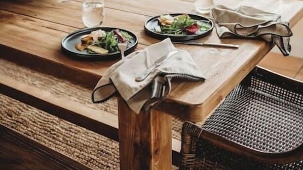 A wooden table with plates of food and glasses, a woven chair, and a view of greenery through a window. - Beautiful 5 Bedroom Home with Pool & Tennis Court (Orange)