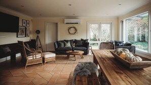 A living room with a sofa, coffee table, and a dining table with pumpkins. - Beautiful 5 Bedroom Home with Pool & Tennis Court (Orange)