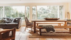 A spacious living area with a large window, a wooden dining table, and a sofa. - Beautiful 5 Bedroom Home with Pool & Tennis Court (Orange)