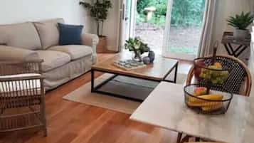 Una sala de estar con sofá, mesa de centro y comedor con sillas.