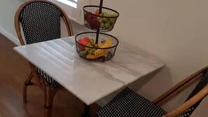 A dining table with two chairs, a fruit basket, and a window with blinds. - Stylish Sale Street Studio - Walk to Town (Orange)