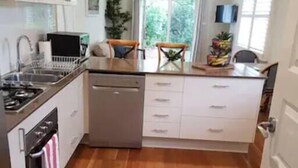 Une cuisine compacte équipée d’un lave-vaisselle, d’une cuisinière et d’un coin repas avec une table et des chaises.