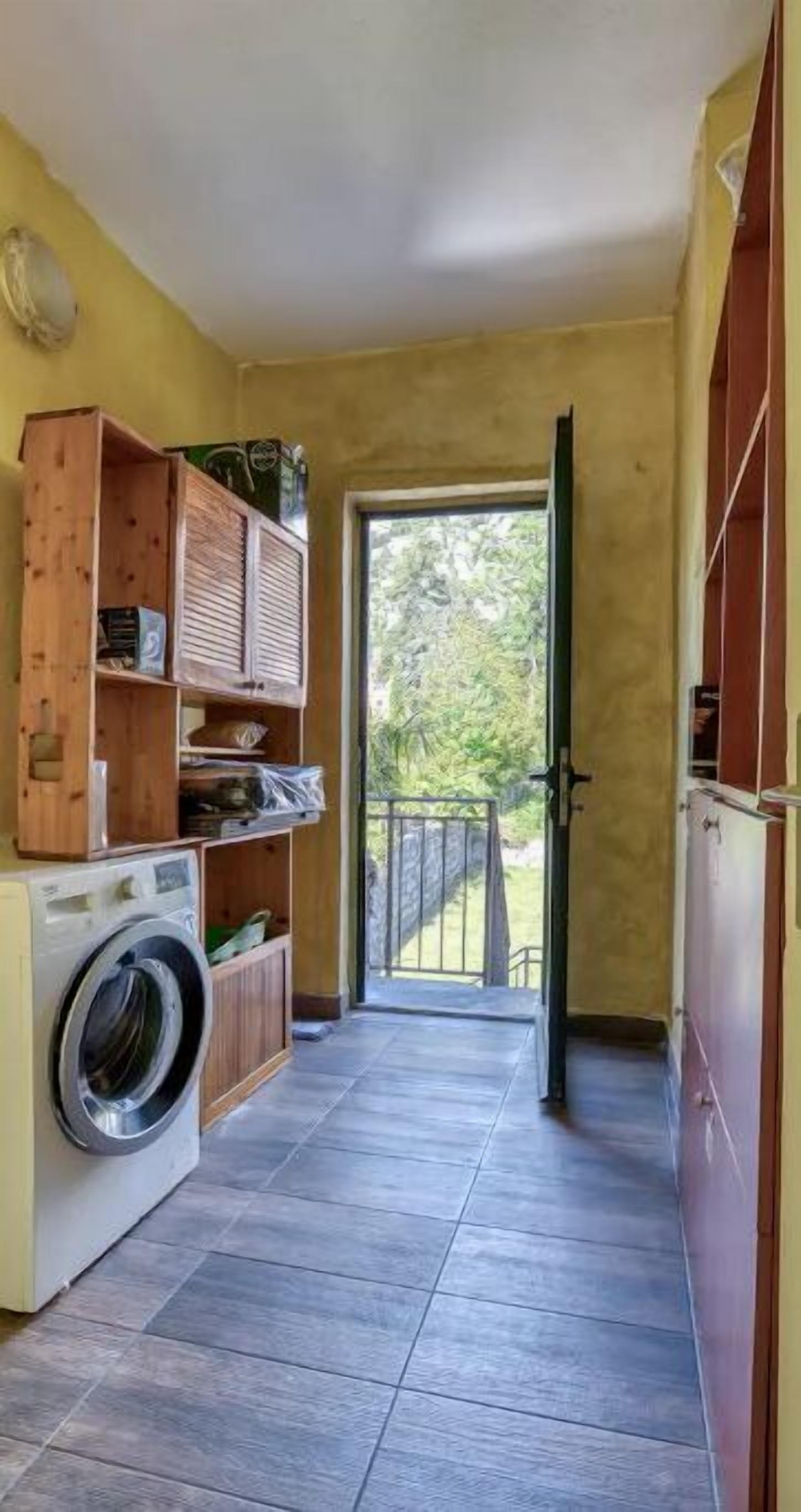 A laundry area with a washing machine, wooden cabinets, and a view of the outdoors.