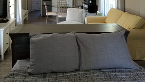 Un salón amplio con una cama grande, un sofá y una zona de comedor con una cocina al fondo.