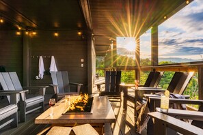 An outdoor seating area with wooden tables and chairs, a fire feature, and a view of the landscape. - Swim Spa/Luxe Design/Views/GameRoom/Theater - Bear Bottom (Gatlinburg)