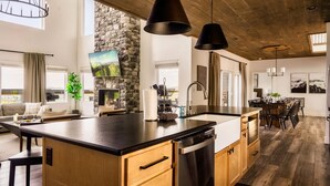 A modern kitchen with a large island, wooden cabinets, and pendant lighting. - Swim Spa/Luxe Design/Views/GameRoom/Theater - Bear Bottom (Gatlinburg)
