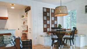 A cozy dining area with a wooden table and chairs, surrounded by white walls and a decorative panel. - Charming Fox Cottage w/ Wood Burning Fireplace (Idyllwild-Pine Cove)